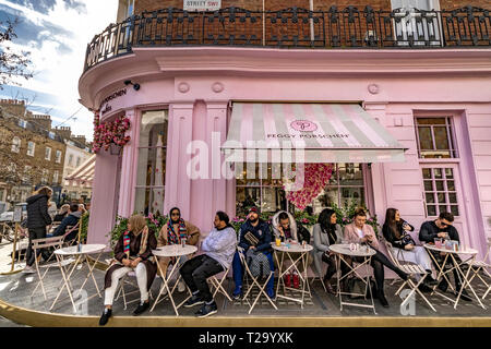 Persone che siedono fuori Peggy Porschen torte, a Belgravia , un negozio di torte noto per il suo impressionante esterno color rosa pastello, Londra, Regno Unito Foto Stock