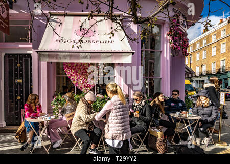 Persone che siedono fuori Peggy Porschen torte, a Belgravia , un negozio di torte noto per il suo impressionante esterno color rosa pastello, Londra, Regno Unito Foto Stock