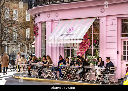 Persone che siedono fuori Peggy Porschen torte, a Belgravia , un negozio di torte noto per il suo impressionante esterno color rosa pastello, Londra, Regno Unito Foto Stock