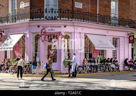 Persone che siedono fuori Peggy Porschen torte, a Belgravia , un negozio di torte noto per il suo impressionante esterno color rosa pastello, Londra, Regno Unito Foto Stock