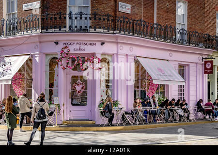 Persone che siedono fuori Peggy Porschen torte, a Belgravia , un negozio di torte noto per il suo impressionante esterno color rosa pastello, Londra, Regno Unito Foto Stock