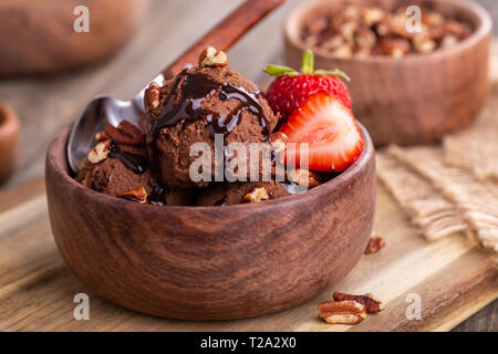 Primo piano di un gelato al cioccolato gelato con fragole fresche in una ciotola di legno Foto Stock