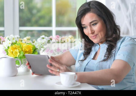 Bella donna matura utilizzando i moderni tablet Foto Stock