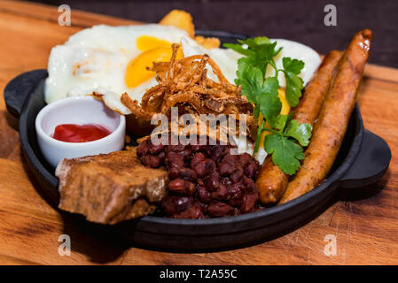 Sostanziosa pasto con uova fritte, salsicce, fagioli, anelli di cipolla e salsa Foto Stock