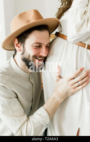 Giovane bella donna incinta in hat in piedi vicino al muro bianco e cactus Foto Stock