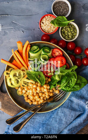 Ciotola di Buddha con ceci, baby spinaci e altre verdure organiche su calcestruzzo con uno sfondo con spazio di copia Foto Stock