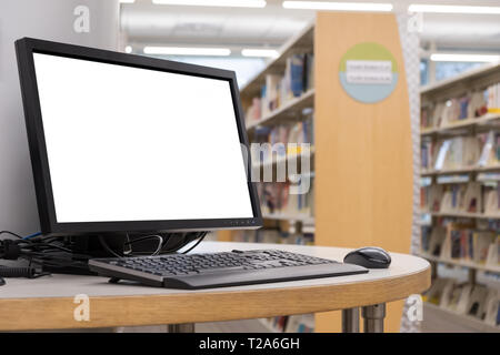 Computer con schermo vuoto monitor sul tavolo in libreria interna Foto Stock