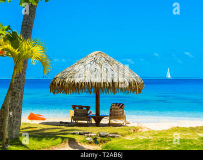 Ombrello di paglia sulla spiaggia nella laguna Huahine, Polinesia Francese Foto Stock