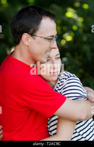 Uomo in camicia rossa abbracciando la moglie Foto Stock