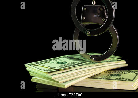 Le manette erano appesi su una banconota del dollaro nelle tenebre dello sfondo. Copia spazio per il testo o gli oggetti. Concetto di frode o corruzione. Foto Stock