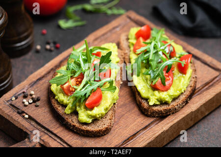 Vegana Vegetariana o toast con purea di avocado, rucola servita sulla tavola di legno Foto Stock