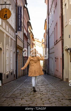 La ragazza di un beige hat e ricoprire nella strada stretta della città di Praga, Repubblica Ceca Foto Stock