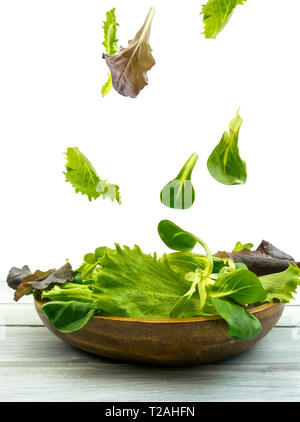 Esplosione di insalata con rucola, barbabietole, spinaci e i germogli in bright tavola di legno su sfondo bianco Foto Stock