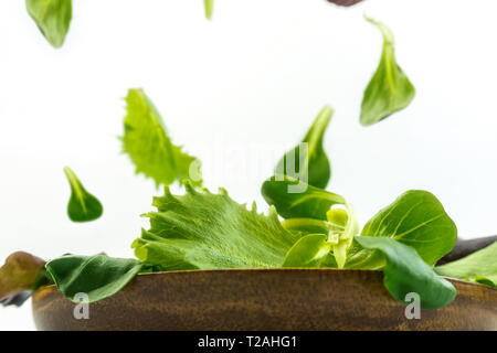 Esplosione di insalata con rucola, barbabietole, spinaci e i germogli in bright tavola di legno su sfondo bianco Foto Stock