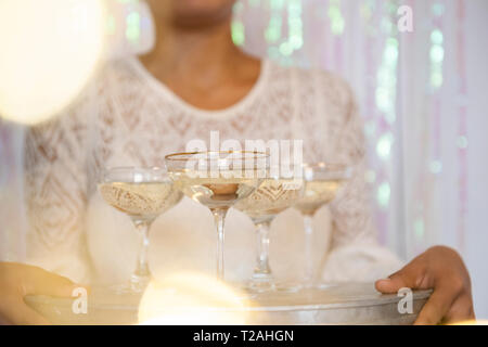 Giovane donna tenendo il vassoio con i bicchieri di vino bianco Foto Stock