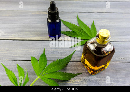 La canapa leafs sul tavolo di legno, olio di cannabis estratti in bottiglie Foto Stock