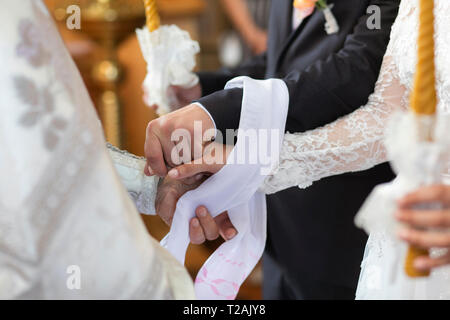 Le mani della sposa e lo sposo legato insieme durante la cerimonia di nozze Foto Stock