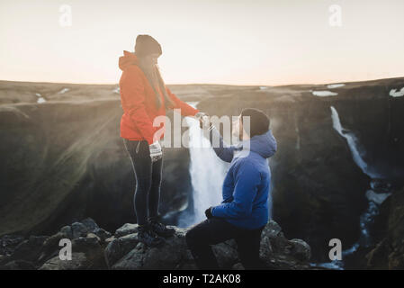 Giovane uomo propone alla sua ragazza mentre escursionismo da Haifoss cascata in Islanda Foto Stock
