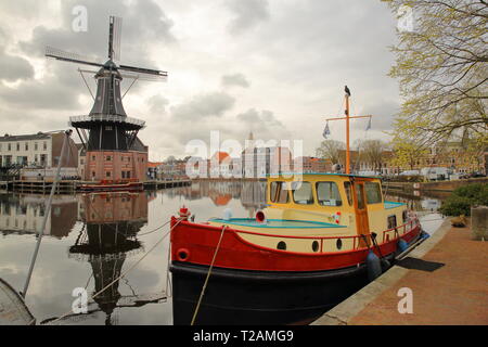 De Adriaan windmill riflettendo sul fiume Spaarne in Haarlem, Paesi Bassi, con un colorato houseboat in primo piano Foto Stock