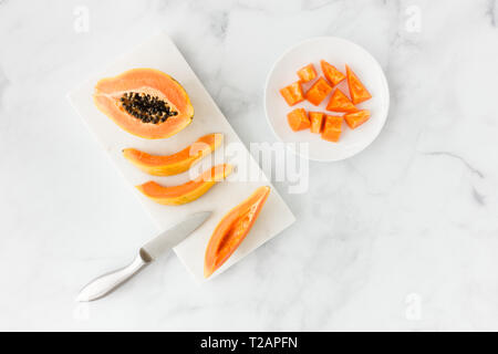 Tagliare la papaia su marmo bianco tagliere e la piastra con un sacco di spazio copia. Vista dall'alto. Foto Stock