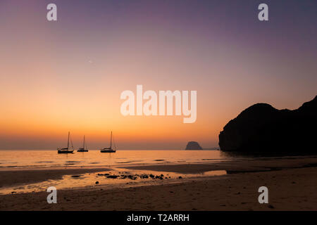 Tropical golden sunset su Koh Mook island in Thailandia. Paesaggio con barche prese su Charlie beach, Haad Sai Yao - Haad Farang. Foto Stock