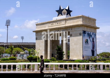 ACCRA, GHANA - 11 Aprile 2018: nero non identificato uomo cammina passato arco di Black Star Gate monumento simbolo di libertà e di parte di Piazza Indipendenza Foto Stock