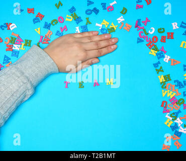 Femmina e a mano in legno multicolore lettere dell'alfabeto inglese su uno sfondo blu, il team di iscrizione Foto Stock