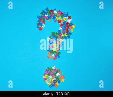 Punto interrogativo figura da piccole in legno multicolore lettere dell'alfabeto inglese su uno sfondo blu Foto Stock