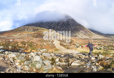 Un escursionista salta sulle rocce di attraversare un flusso nella Mourne Mountains in Irlanda del Nord, Regno Unito. Foto Stock