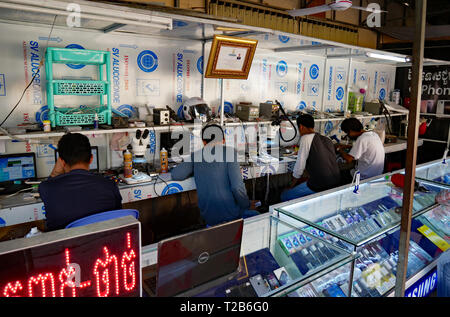 Battambang, Cambogia. I tecnici di riparazione telefoni mobili in un aperto Khmer fronteggiata phone shop. 15-12-2018 Foto Stock