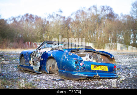 Un vecchio scatafascio auto sportiva si siede a terra a abbandonato Furber's Scrapyard nello Shropshire, Inghilterra. Foto Stock