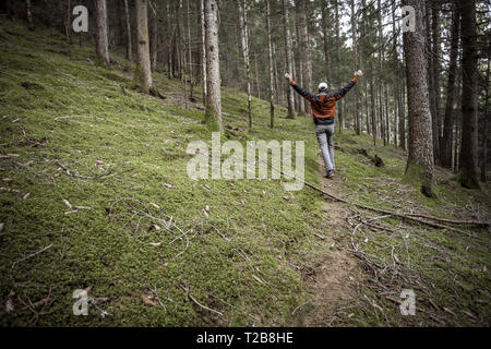 Un trekker camminare da solo tra la foresta in un giorno nuvoloso Foto Stock