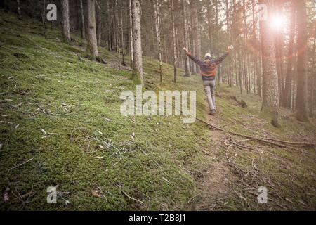 Un trekker camminare da solo tra la foresta in un giorno nuvoloso Foto Stock