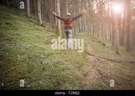 Un trekker camminare da solo tra la foresta in un giorno nuvoloso Foto Stock