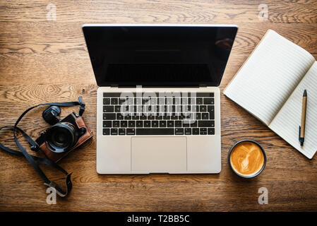 Ufficio tavolo di lavoro con computer, fotocamera e la tazza di caffè. Vista superiore Foto Stock