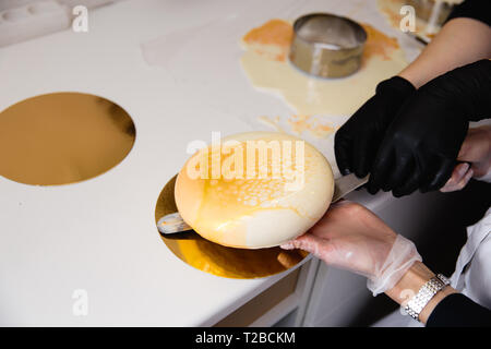 Mousse di torta di yogurt. Ragazze cook e creano un disegno di mousse sulla torta. Specchio congelati ciliegina sulla torta. Capolavori culinari Foto Stock