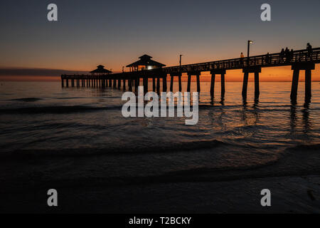Il molo presso la spiaggia di Fort Myers contro la sera presto al tramonto, twilight colori e dolci onde dell'oceano. Foto Stock
