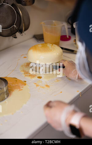 Mousse di torta di yogurt. Ragazze cook e creano un disegno di mousse sulla torta. Specchio congelati ciliegina sulla torta. Capolavori culinari Foto Stock