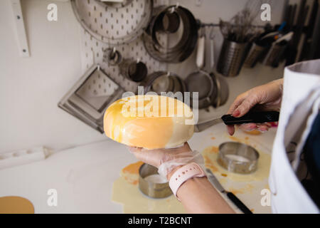 Mousse di torta di yogurt. Ragazze cook e creano un disegno di mousse sulla torta. Specchio congelati ciliegina sulla torta. Capolavori culinari Foto Stock