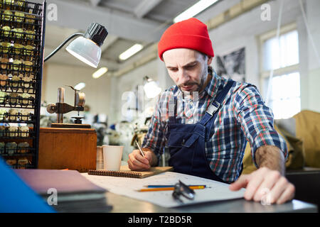 Lavoratore di piani di disegno presso la fabbrica Foto Stock