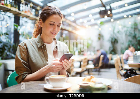 Pretty Woman controllo messenger in cafe Foto Stock