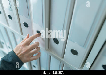 Imprenditrice navigando attraverso il ring binder file archivio di documentazione o il ripiano in ufficio business, stretta di mano Foto Stock