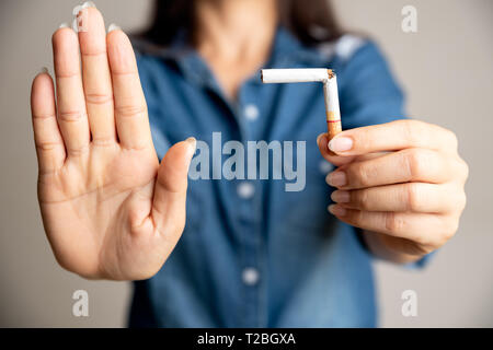 Celebra la Giornata Mondiale senza tabacco, 31 maggio. Smettere di fumare. Close up donna rottura a mano, schiacciamento o distruggendo le sigarette. Foto Stock