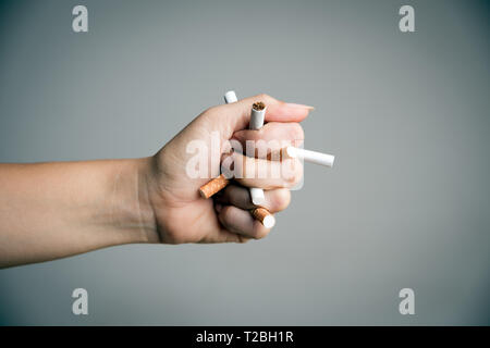 Celebra la Giornata Mondiale senza tabacco, 31 maggio. Smettere di fumare. Close up man mano la frantumazione e la distruzione di sigarette su sfondo grigio. Foto Stock