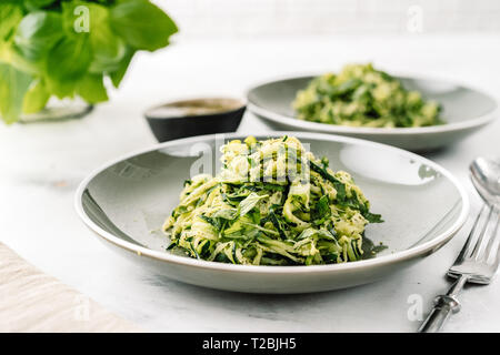 Zucchine vegan pasta in due piastre su sfondo bianco. Vegetariano cibo sano Foto Stock