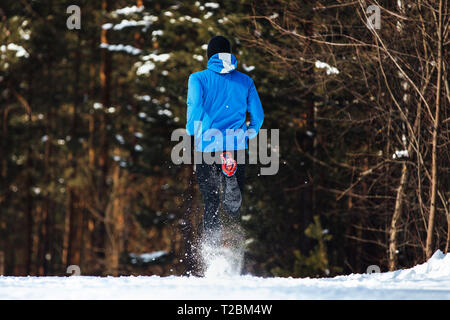 Torna atleta runner acceso sentiero invernale neve spray mosche Foto Stock