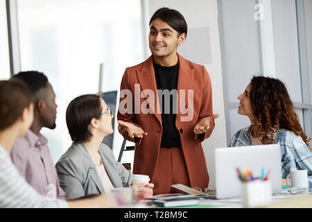 Ritratto di successo imprenditore mediorientale dando la presentazione ai colleghi durante la riunione in ufficio, spazio di copia Foto Stock