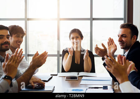 Businesspersons battendo le mani e applaudire in business sale conferenza. Mentre la femmina executive business si siede di fronte - donna potenza in corporate Foto Stock