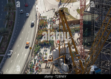 Arial vista di un grande gruppo di lavoratori edili, raggruppati sul lato della strada durante un drill incendio Foto Stock