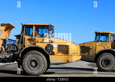 Lieto, Finlandia - 22 Marzo 2019: due Volvo Dumpers articolati, A35D e A35E, passare a velocità da un sito in costruzione, vista laterale. Foto Stock